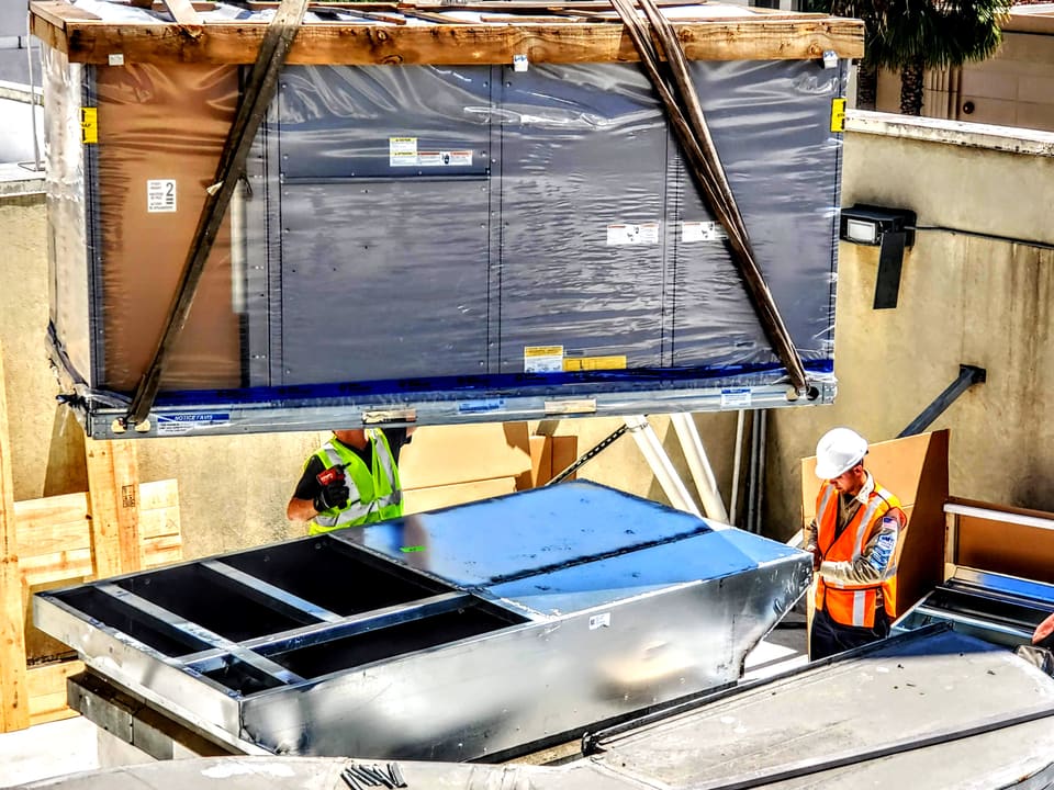Crew installing large commercial rooftop HVAC equipment